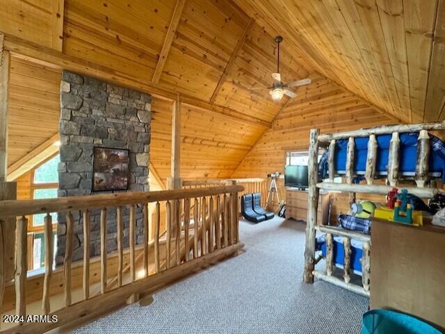 interior space featuring carpet floors, lofted ceiling, wood walls, and wooden ceiling