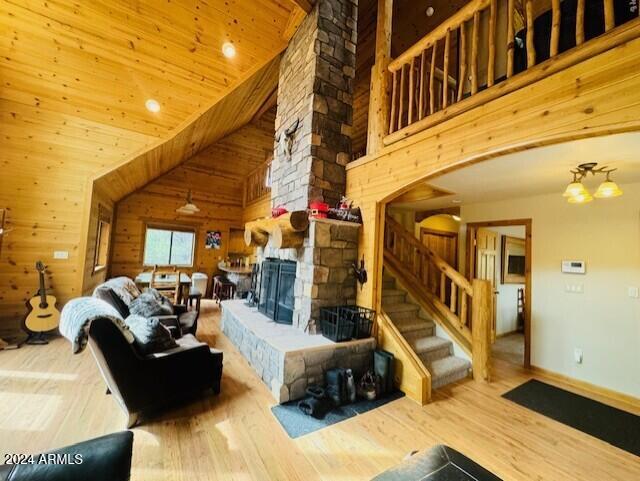 living room with wood walls, high vaulted ceiling, wooden ceiling, a fireplace, and hardwood / wood-style floors