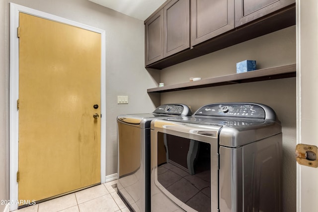 washroom featuring washer and clothes dryer, light tile patterned floors, and cabinets