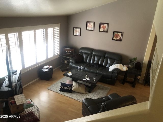 living room featuring lofted ceiling, baseboards, and wood finished floors