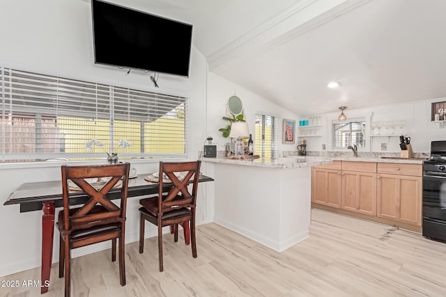 kitchen with gas stove, light brown cabinetry, light hardwood / wood-style floors, sink, and kitchen peninsula