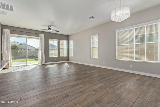 empty room with ceiling fan with notable chandelier and a healthy amount of sunlight