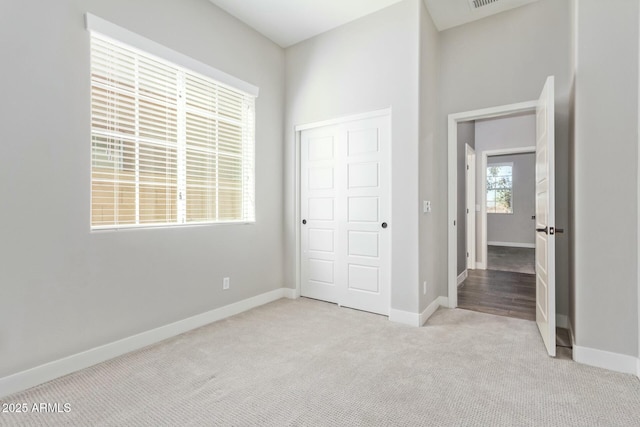 unfurnished bedroom with light colored carpet and a closet