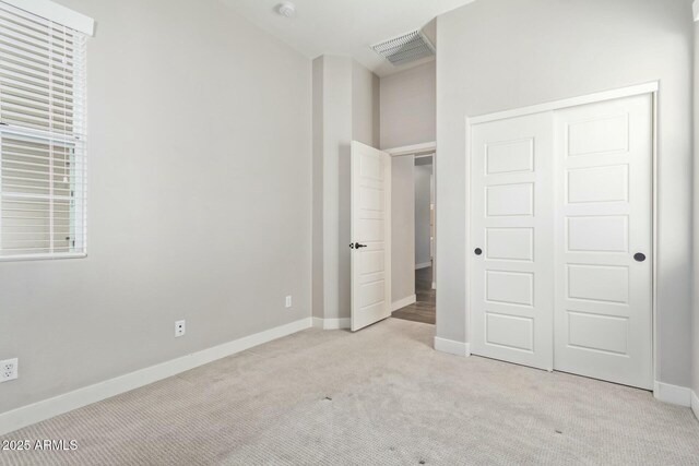 unfurnished bedroom featuring a closet and light colored carpet