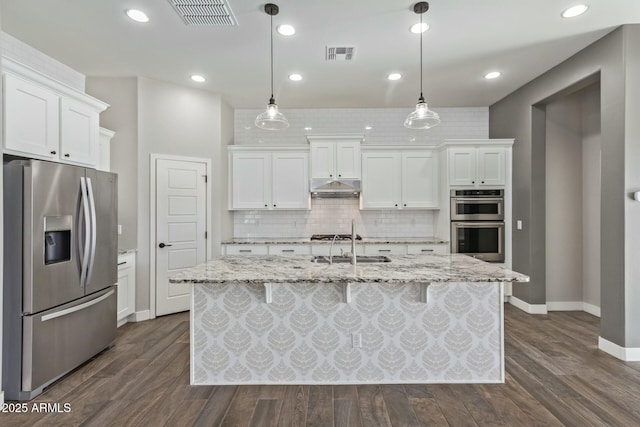 kitchen featuring a center island with sink, white cabinets, appliances with stainless steel finishes, and pendant lighting