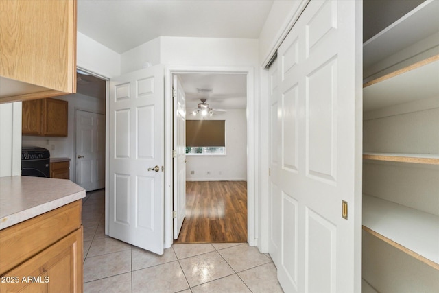 kitchen with washer / dryer, light tile patterned flooring, and ceiling fan