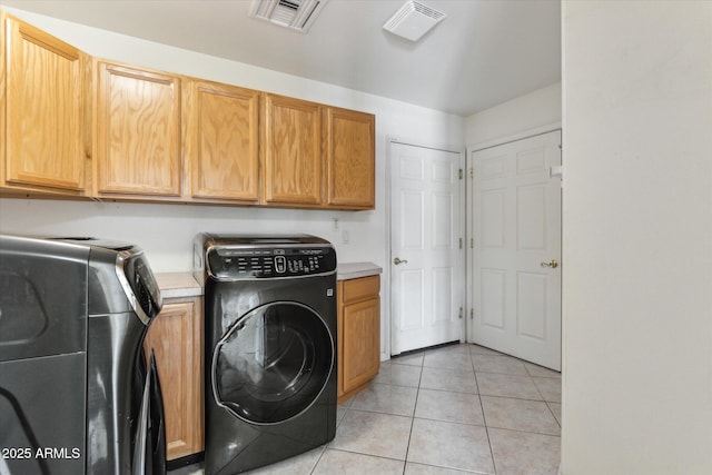 clothes washing area featuring cabinets, light tile patterned flooring, and independent washer and dryer