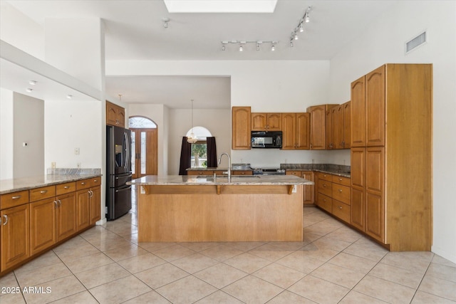 kitchen with sink, light tile patterned flooring, a center island with sink, a high ceiling, and appliances with stainless steel finishes