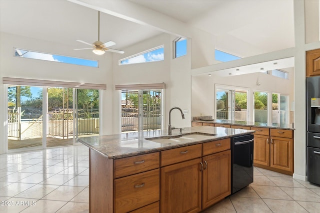 kitchen with sink, dishwasher, a wealth of natural light, light stone countertops, and a center island with sink