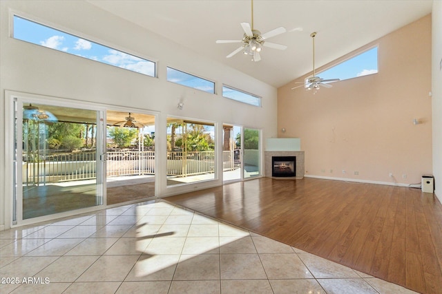 unfurnished living room featuring a high ceiling, light tile patterned flooring, a tile fireplace, and plenty of natural light