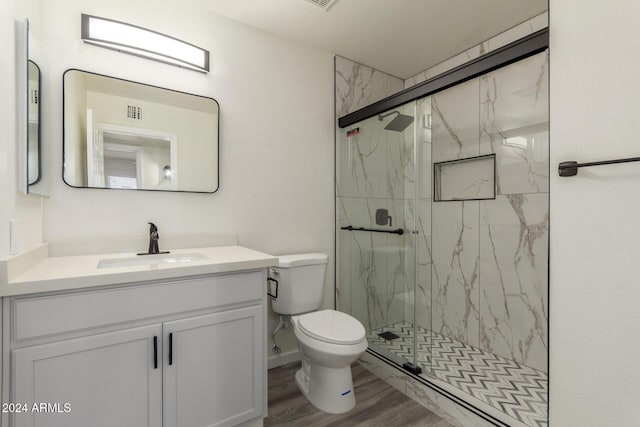 bathroom featuring hardwood / wood-style flooring, vanity, toilet, and a shower with shower door