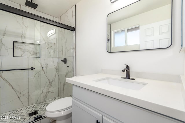 bathroom with vanity, toilet, and a shower with door