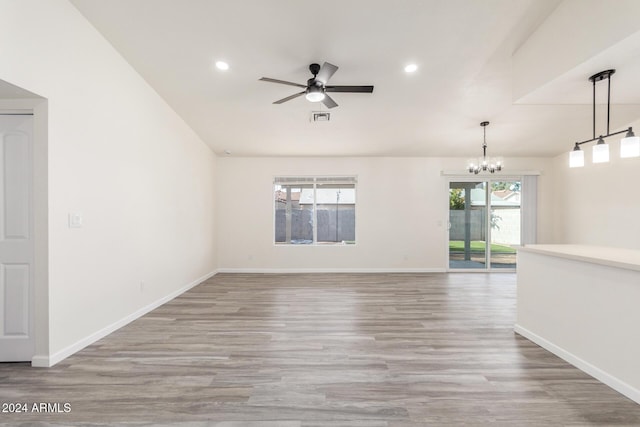 unfurnished room featuring hardwood / wood-style floors and ceiling fan with notable chandelier