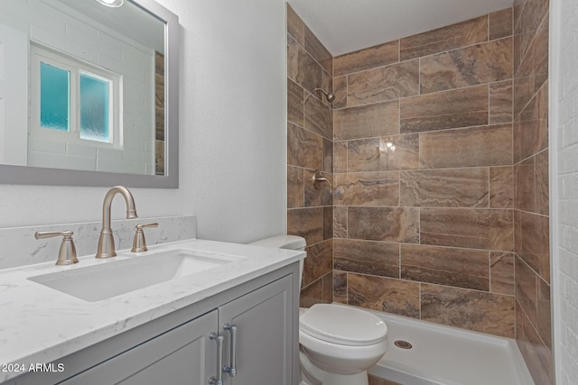 bathroom with vanity, toilet, and tiled shower