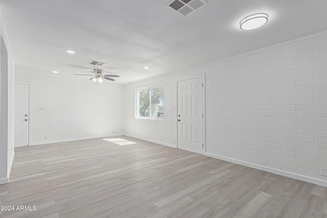 empty room with light hardwood / wood-style flooring, brick wall, and ceiling fan