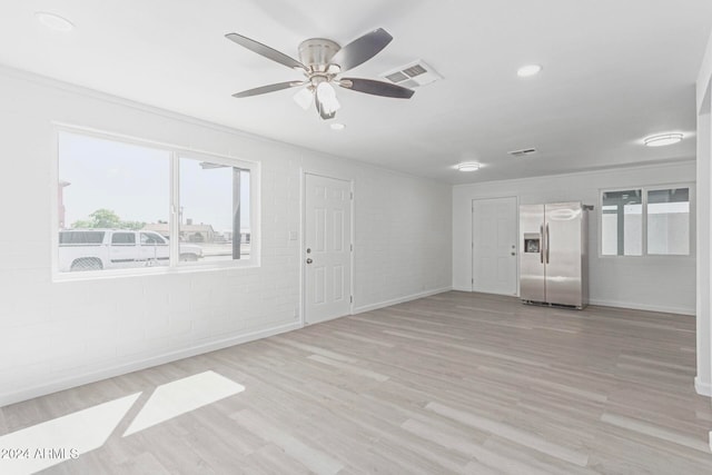 unfurnished room with light hardwood / wood-style floors, brick wall, and ceiling fan