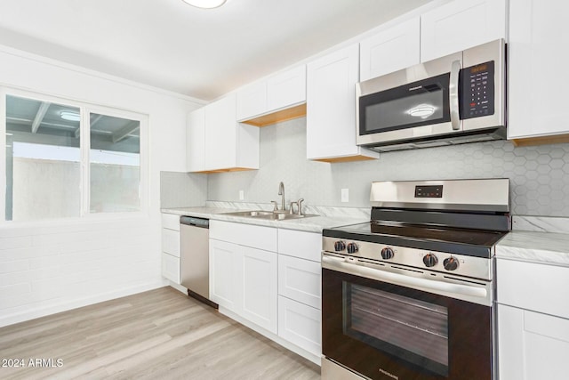 kitchen with light stone counters, sink, white cabinetry, light wood-type flooring, and appliances with stainless steel finishes