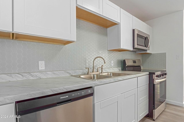 kitchen with white cabinets, sink, light wood-type flooring, and appliances with stainless steel finishes