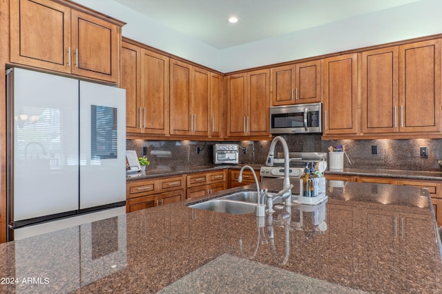 kitchen featuring stainless steel appliances, dark stone counters, and backsplash