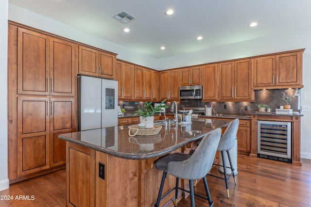 kitchen with wine cooler, a center island with sink, dark hardwood / wood-style flooring, backsplash, and white refrigerator