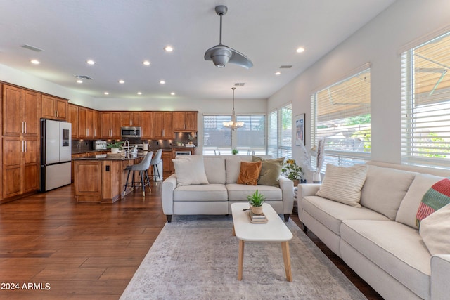 living room featuring dark wood-type flooring, sink, and a chandelier