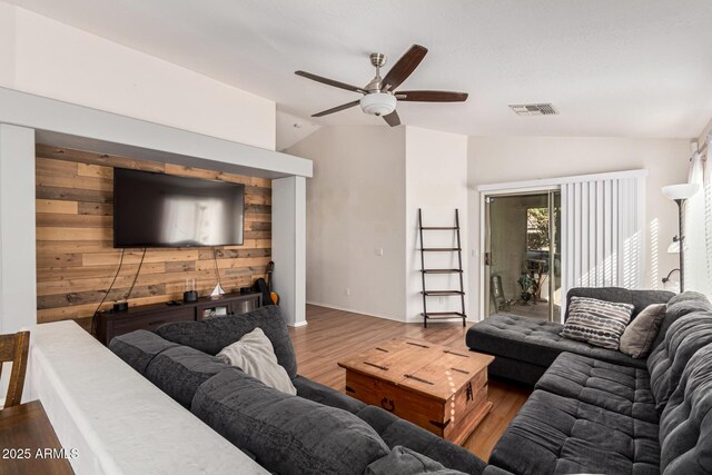 living room featuring wooden walls, hardwood / wood-style flooring, ceiling fan, and vaulted ceiling