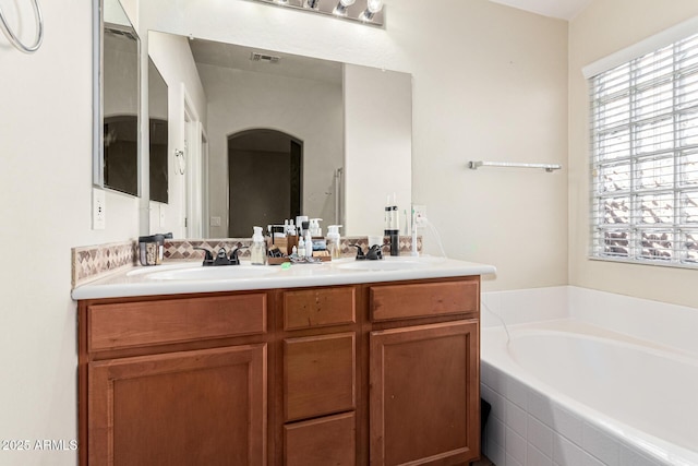 bathroom with vanity and tiled bath