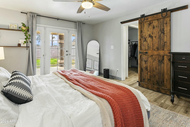 bedroom featuring access to exterior, ceiling fan, a barn door, light hardwood / wood-style floors, and a closet