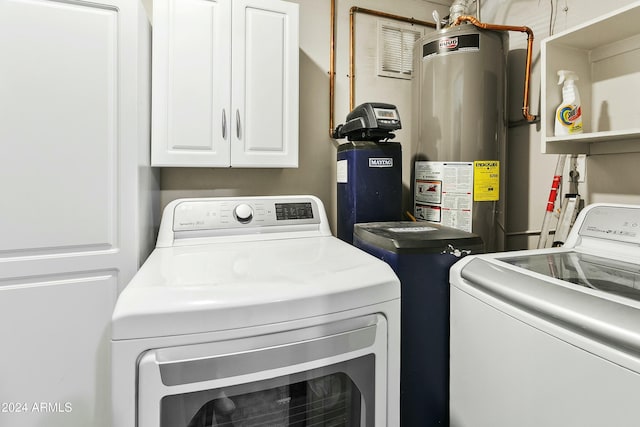 laundry room featuring water heater, cabinets, and independent washer and dryer