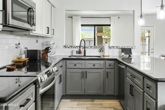 kitchen featuring gray cabinetry, sink, decorative light fixtures, decorative backsplash, and appliances with stainless steel finishes