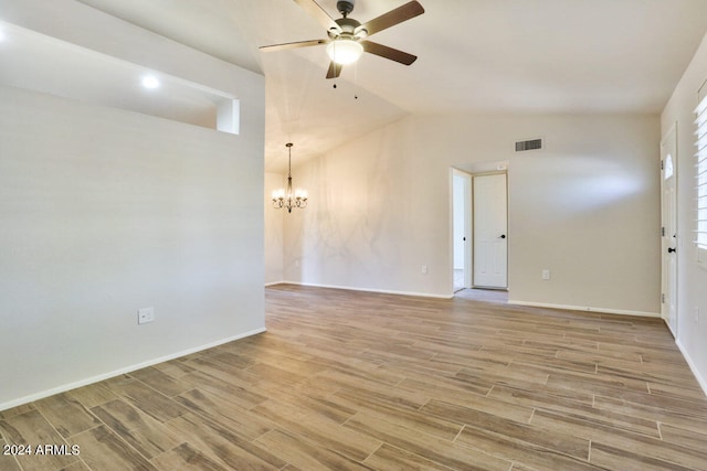 spare room with light hardwood / wood-style floors, ceiling fan with notable chandelier, and vaulted ceiling