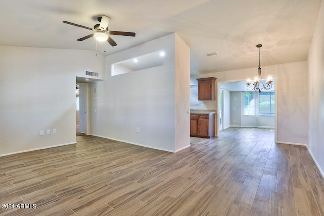 unfurnished living room with vaulted ceiling, ceiling fan with notable chandelier, and hardwood / wood-style floors