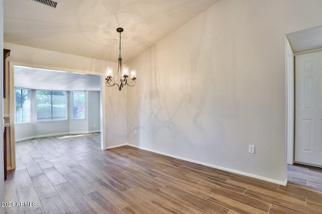 unfurnished room with an inviting chandelier, wood-type flooring, and lofted ceiling