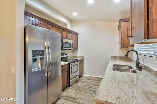 kitchen featuring sink, light stone countertops, stainless steel appliances, and light hardwood / wood-style floors