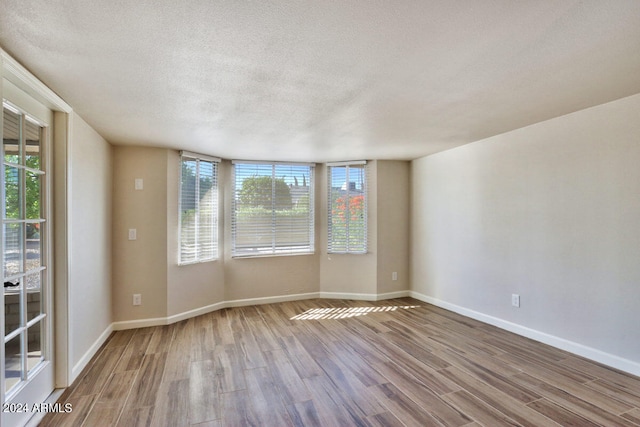 unfurnished room featuring light hardwood / wood-style floors and a textured ceiling