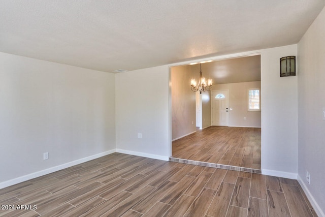 spare room featuring a textured ceiling, a chandelier, and wood-type flooring