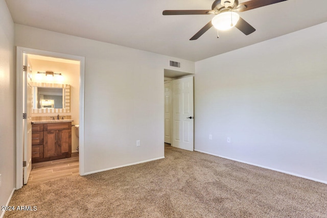 unfurnished bedroom with sink, light carpet, ceiling fan, and ensuite bath