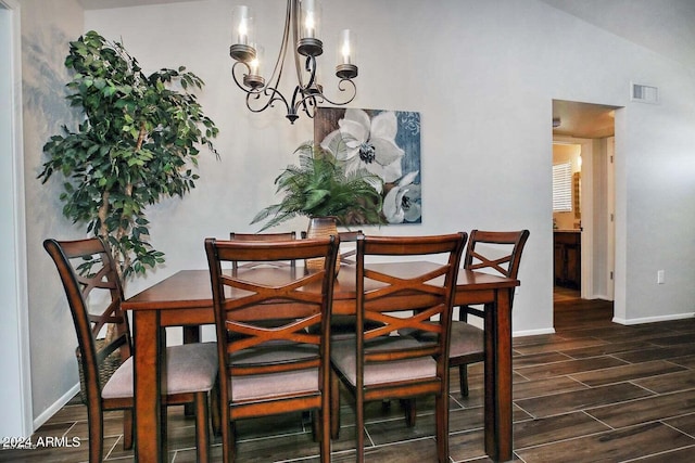 dining area featuring vaulted ceiling, an inviting chandelier, and dark hardwood / wood-style floors