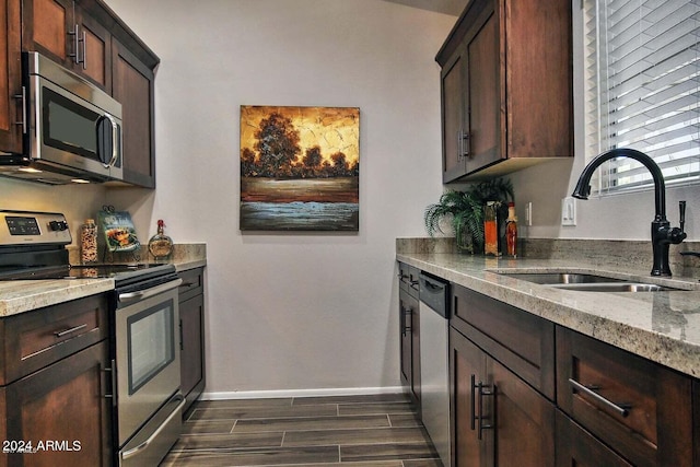 kitchen featuring light stone countertops, appliances with stainless steel finishes, sink, dark brown cabinets, and dark hardwood / wood-style floors