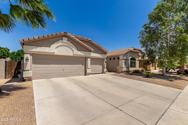 mediterranean / spanish-style house with stucco siding, driveway, a garage, and a tiled roof