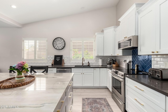 kitchen featuring appliances with stainless steel finishes, a sink, backsplash, dark stone counters, and recessed lighting