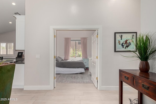 corridor with light wood-type flooring, baseboards, healthy amount of natural light, and recessed lighting