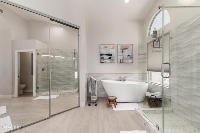full bath with a shower stall, a soaking tub, toilet, and tile walls