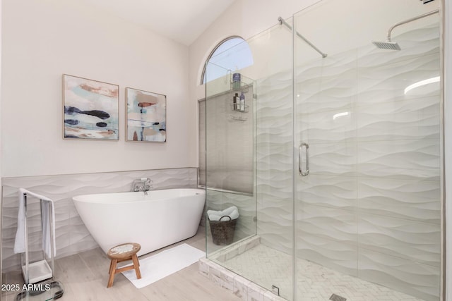 bathroom featuring a shower stall, a soaking tub, and tile walls