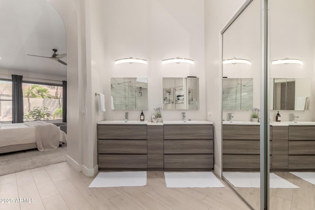 ensuite bathroom featuring two vanities, baseboards, and ceiling fan