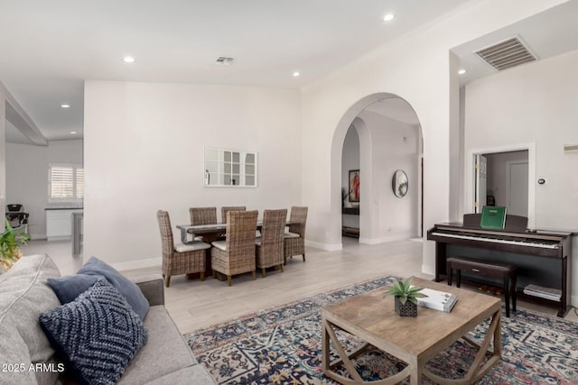 living room with recessed lighting, arched walkways, light wood-style flooring, and baseboards