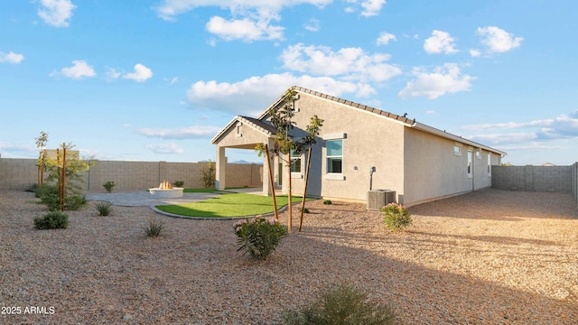 back of property featuring a fenced backyard, a patio, a fire pit, and stucco siding