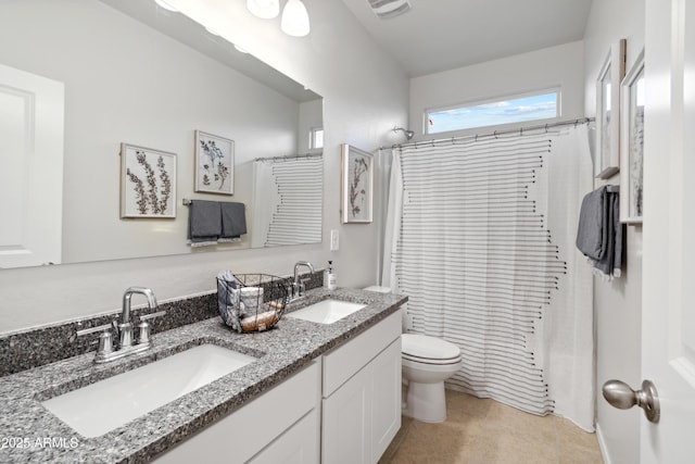 full bath with toilet, double vanity, visible vents, and a sink