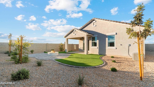 back of property with a fenced backyard, central air condition unit, a fire pit, stucco siding, and a patio area