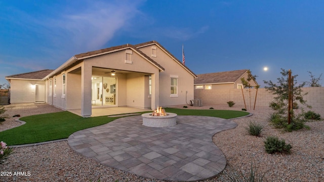 rear view of property with a patio, an outdoor fire pit, fence, and stucco siding